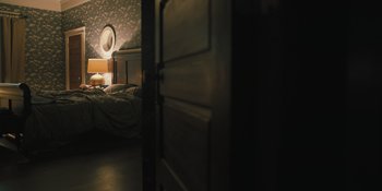 Movie still from “Hereditary” (2018), directed by Ari Aster – A bed room with a bed and a lamp in the corner; Wide shot, High angle