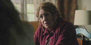 Movie still from “Hereditary” (2018), directed by Ari Aster – An older woman wearing a red shirt and a tie; Close Up shot, Over the shoulder angle