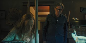 Movie still from “Hereditary” (2018), directed by Ari Aster – A man and a woman standing next to each other on a train; Medium shot, Over the shoulder angle