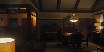 Movie still from “Hereditary” (2018), directed by Ari Aster – Two people sitting at a table in a dark room; Wide shot, High angle