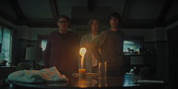 Movie still from “Hereditary” (2018), directed by Ari Aster – Three people standing in front of a lit candle; Medium shot, Low angle