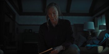 Movie still from “Hereditary” (2018), directed by Ari Aster – A woman sitting on the ground holding a stick; Medium shot, High angle