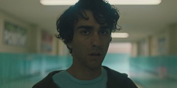 Movie still from “Hereditary” (2018), directed by Ari Aster – A young man with curly black hair stares into the camera; Close Up shot, Low angle