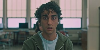 Movie still from “Hereditary” (2018), directed by Ari Aster – A young man with curly brown hair wearing a green hoodie; Close Up shot, Low angle