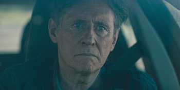 Movie still from “Hereditary” (2018), directed by Ari Aster – An older man with a serious look on his face; Close Up shot, Over the shoulder angle