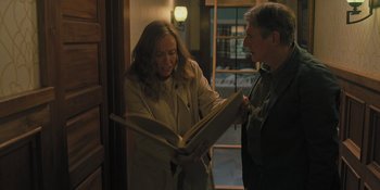 Movie still from “Hereditary” (2018), directed by Ari Aster – A man and a woman looking at a book; Medium shot, High angle