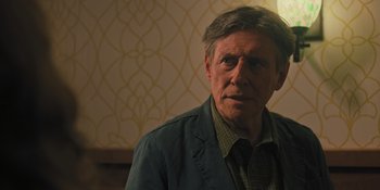 Movie still from “Hereditary” (2018), directed by Ari Aster – An older man wearing a jacket and a plaid shirt; Close Up shot, Over the shoulder angle