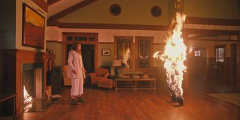 Movie still from “Hereditary” (2018), directed by Ari Aster – A woman standing in front of a fire in a living room; Wide shot, High angle