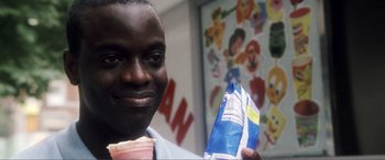 Movie still from “Hitch” (2005), directed by Andy Tennant – A man holding a bag of food in front of a painting; Close Up shot, High angle