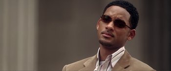 Movie still from “Hitch” (2005), directed by Andy Tennant – A person wearing a suit and sunglasses; Close Up shot, Over the shoulder angle