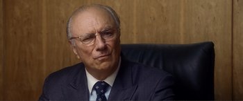Movie still from “Hitch” (2005), directed by Andy Tennant – An older man wearing a suit and tie sitting in an office chair; Close Up shot, Over the shoulder angle