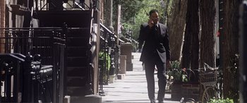 Movie still from “Hitch” (2005), directed by Andy Tennant – A man walking down a sidewalk while talking on a cell phone; Wide shot, Low angle