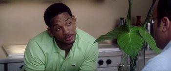 Movie still from “Hitch” (2005), directed by Andy Tennant – A man sitting in front of a plant in a room; Close Up shot, Over the shoulder angle