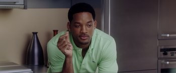 Movie still from “Hitch” (2005), directed by Andy Tennant – A man in a green shirt is sitting down; Close Up shot, Over the shoulder angle