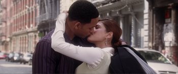 Movie still from “Hitch” (2005), directed by Andy Tennant – A man and a woman kissing in front of a building; Medium shot, High angle