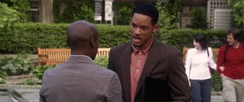 Movie still from “Hitch” (2005), directed by Andy Tennant – A man in a brown suit talking to another man in a pink shirt; Medium shot, Over the shoulder angle