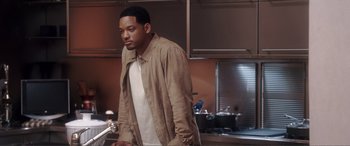 Movie still from “Hitch” (2005), directed by Andy Tennant – A man standing in a kitchen next to a sink; Medium shot, Over the shoulder angle