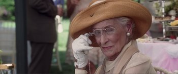 Movie still from “Hitch” (2005), directed by Andy Tennant – An older woman wearing a hat and holding a cell phone to her ear; Close Up shot, Over the shoulder angle