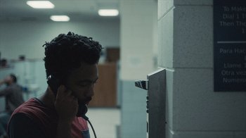 Movie still from “Atlanta” (2016), created by Donald Glover – A man talking on a phone next to a wall; Close Up shot, Over the shoulder angle