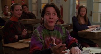 Movie still from “Hocus Pocus” (1993), directed by Kenny Ortega – A young man sitting at a table in front of a group of people; Medium shot, Over the shoulder angle