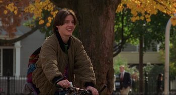 Movie still from “Hocus Pocus” (1993), directed by Kenny Ortega – A man riding a bike next to a large tree; Medium shot, Over the shoulder angle