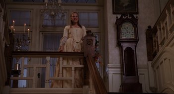 Movie still from “Hocus Pocus” (1993), directed by Kenny Ortega – A woman standing on top of a railing next to a grandfather clock; Wide shot, Low angle