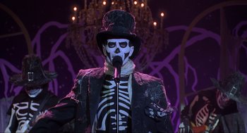 Movie still from “Hocus Pocus” (1993), directed by Kenny Ortega – A man in a skeleton costume and top hat singing into a microphone; Medium shot, Low angle