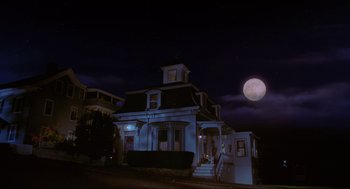 Movie still from “Hocus Pocus” (1993), directed by Kenny Ortega – A house that is lit up at night with the moon in the background; Wide shot, Low angle