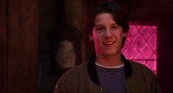 Movie still from “Hocus Pocus” (1993), directed by Kenny Ortega – A young man smiling for the camera in front of a building; Close Up shot, Low angle