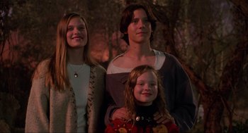 Movie still from “Hocus Pocus” (1993), directed by Kenny Ortega – A woman and two girls standing next to each other in front of trees; Medium shot, Low angle