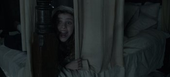 Movie still from “Hocus Pocus 2” (2022), directed by Anne Fletcher – A young girl peeking out from behind a curtain; Medium shot, Low angle
