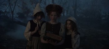Movie still from “Hocus Pocus 2” (2022), directed by Anne Fletcher – A woman and two young girls holding an open book; Medium shot, Low angle