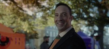 Movie still from “Hocus Pocus 2” (2022), directed by Anne Fletcher – A man in a suit and tie smiling for the camera; Close Up shot, Over the shoulder angle