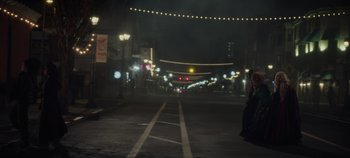 Movie still from “Hocus Pocus 2” (2022), directed by Anne Fletcher – A city street at night lit up by street lights; Extreme Wide shot, Over the shoulder angle