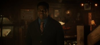 Movie still from “Hocus Pocus 2” (2022), directed by Anne Fletcher – A man wearing a suit and tie in a dark room; Medium shot, Over the shoulder angle