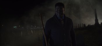Movie still from “Hocus Pocus 2” (2022), directed by Anne Fletcher – A man holding a wooden stick in the dark at night; Medium shot, Over the shoulder angle
