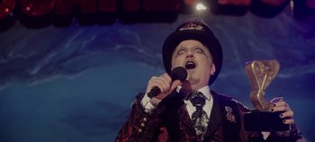 Movie still from “Hocus Pocus 2” (2022), directed by Anne Fletcher – A man in a suit and hat is singing into a microphone; Medium shot, Low angle