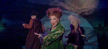 Movie still from “Hocus Pocus 2” (2022), directed by Anne Fletcher – A woman dressed as hocus pocus is posing for a picture; Medium shot, High angle
