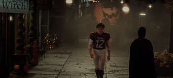 Movie still from “Hocus Pocus 2” (2022), directed by Anne Fletcher – A young football player is walking down the street at night; Wide shot, High angle