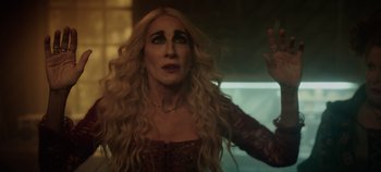Movie still from “Hocus Pocus 2” (2022), directed by Anne Fletcher – A woman with long blonde hair wearing a red and black dress; Close Up shot, Over the shoulder angle