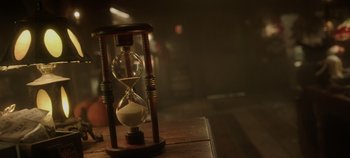 Movie still from “Hocus Pocus 2” (2022), directed by Anne Fletcher – An image of an hourglass sitting on a wooden table; Extreme Close Up shot, High angle