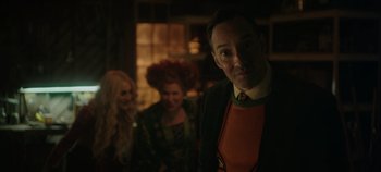 Movie still from “Hocus Pocus 2” (2022), directed by Anne Fletcher – A man and two women are standing in a dimly - lit room; Medium shot, Over the shoulder angle