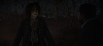 Movie still from “Hocus Pocus 2” (2022), directed by Anne Fletcher – A person with long black hair standing in a dark forest; Medium shot, Over the shoulder angle