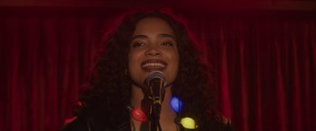Movie still from “Holiday Harmony” (2022), directed by Shaun Paul Piccinino – A woman is singing into a microphone; Close Up shot, Over the shoulder angle