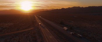 Movie still from “Holiday Harmony” (2022), directed by Shaun Paul Piccinino – An aerial view of a highway at sunset; Extreme Wide shot, High angle