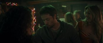 Movie still from “Holiday Harmony” (2022), directed by Shaun Paul Piccinino – A man sitting at a table in front of lights; Close Up shot, Over the shoulder angle