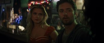 Movie still from “Holiday Harmony” (2022), directed by Shaun Paul Piccinino – A man and a woman standing next to each other in front of lights; Close Up shot, Over the shoulder angle
