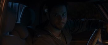 Movie still from “Holiday Harmony” (2022), directed by Shaun Paul Piccinino – A young man is sitting in a car in the dark; Close Up shot, Over the shoulder angle