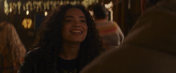 Movie still from “Holiday Harmony” (2022), directed by Shaun Paul Piccinino – A person with curly hair smiling; Close Up shot, Over the shoulder angle