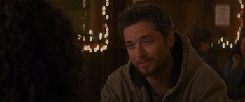 Movie still from “Holiday Harmony” (2022), directed by Shaun Paul Piccinino – A person sitting in front of lights; Close Up shot, Over the shoulder angle